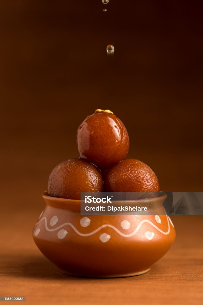 Gulab Jamun in clay pot. Indian Dessert or Sweet Dish Gulab Jamun in clay pot with spoon and dry fruits. Indian Dessert or Sweet Dish Gulab Jamun Stock Photo