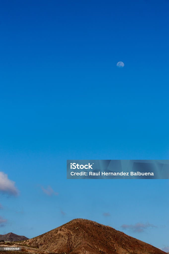 Crisp Full Moon At Sunset Above The Teide Seen From Las Americas Beach. Crisp Full Moon At Sunset Above The Teide Seen From Las Americas Beach. April 11, 2019. Santa Cruz De Tenerife Spain Africa. Travel Tourism Street Photography. Astronomy Stock Photo