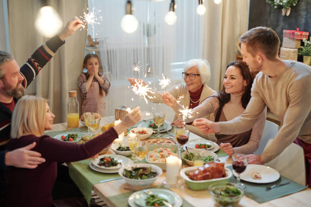 istock Happy young and mature adults with bengal lights sitting by served table 1188005200
