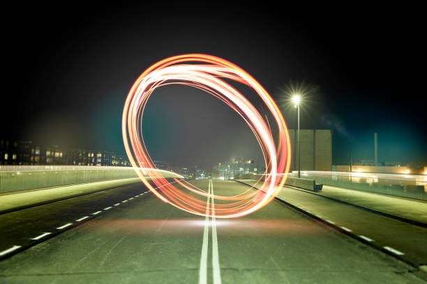 Round light trail in the middle of an abandoned street in a rough environment Big round illuminating phenomenon comes buzzing through the city. Round light stands in the middle of the street in a dark city, on a dark street.. night photography, city lights night. spinning photos stock pictures, royalty-free photos & images