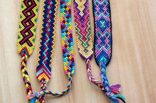 Five handmade homemade colorful natural woven bracelets of friendship on wooden board, group of fashion accessories, various colors