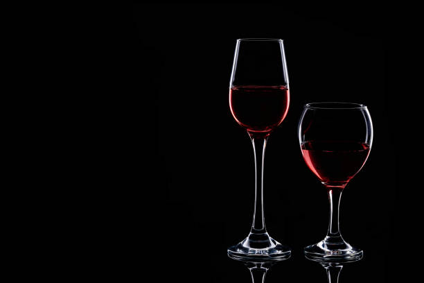 istock Two glasses silhouette with red wine isolated on black background 1188006665