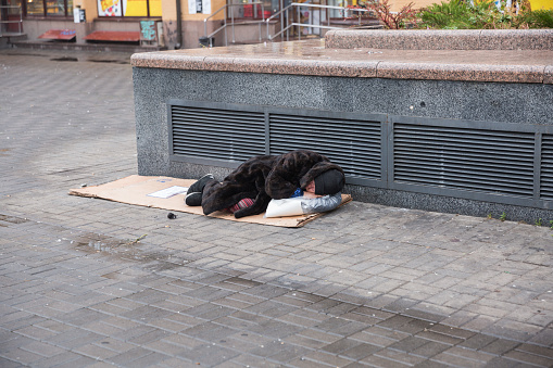 City, Kiev, Ukraine. Homeless person is lying on the street. City center street in the morning. 10.11.2019