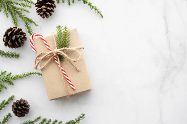 istock White marble table with Christmas decoration including giftbox, candy cane, pine branches and pine cones. Merry Christmas and happy new year concept. Top view with copy space, flat lay. 1188008644
