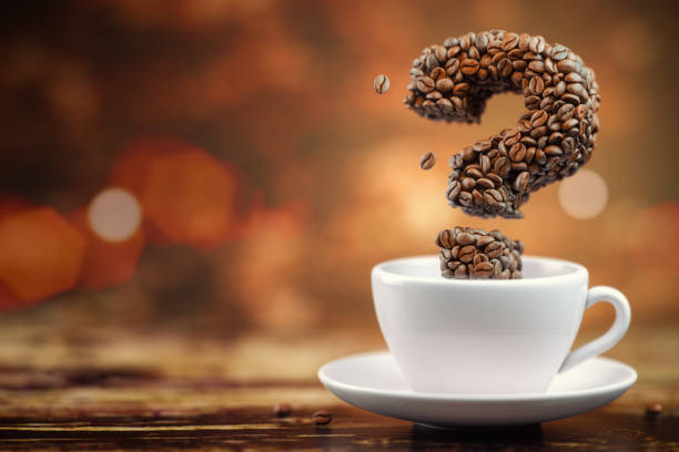Coffee beans in a form of question mark and white cup. FAQ, ask and information about coffee.