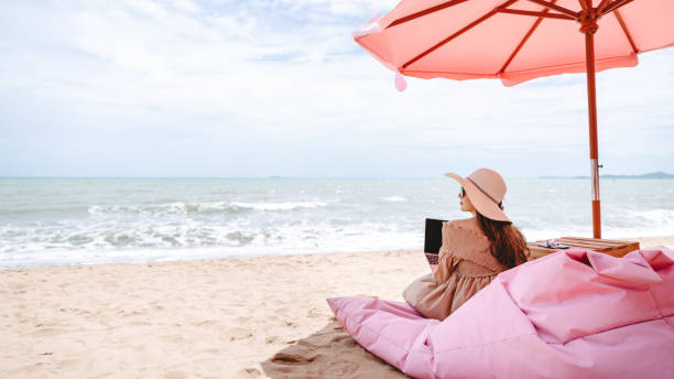 istock Woman with laptop in cafe on beach 1188016201