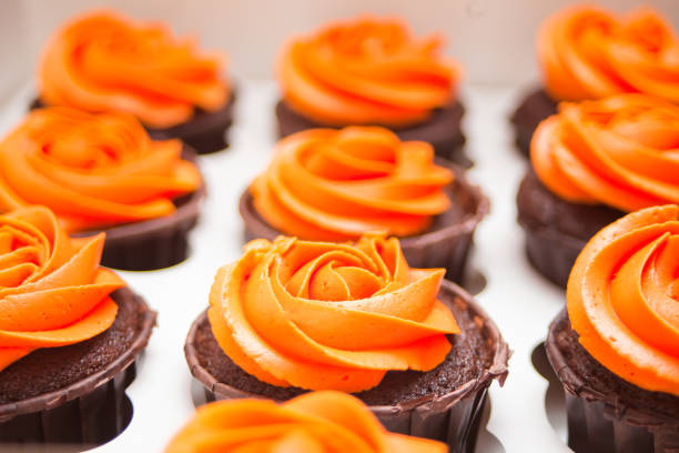 Close up chocolate cupcakes with orange cream in a paper box for gift.