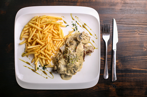 Chicken breast meat in mushroom sauce with french fries meal.