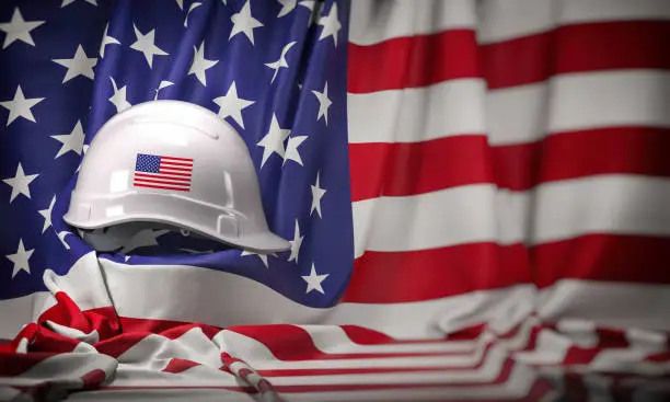 White hard hat laying over USA flag. Construction and employment in United States USA concept, Labor day. 3d illustration