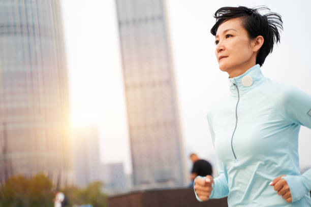 portrait of Asian beauty jogging in city park at sunrise stock photo