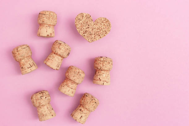 Many corks from champagne and heart on pink paper background with copy space. Flat lay for Birthday, party, wedding. Hen party invitation.