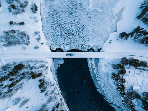 Aerial top view of bridge road above frozen river in snow winter Finland.