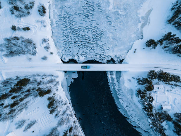 aerial top view of bridge road above frozen river in snow winter finland. - cabin snow finland lapland imagens e fotografias de stock