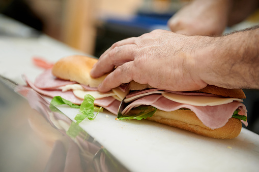 Chef making sandwich showing hands cutting on a board and table with reflection
