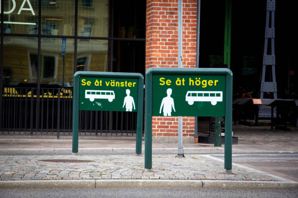 Warning signs informing people on the crosswalk to look left and right, as the buses drive on the wrong side of the road at the bus station outside Malmö central station, Sweden