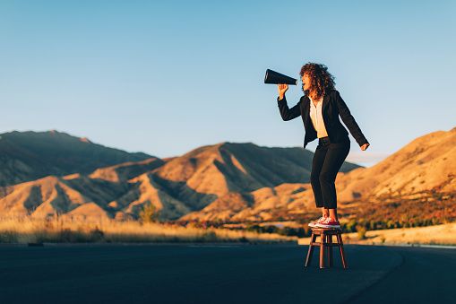 A businesswoman stands alone on a stool in a rural area of Utah shouting through a megaphone waiting to be heard. She is selling an idea that she believes will benefit her business and clients.