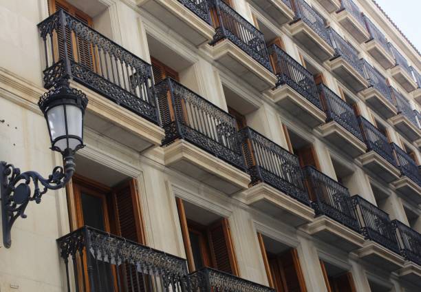 Many forged metal balconies in parallel lines with street light on yellow classic facade