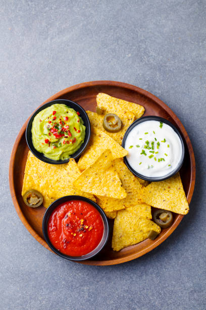Nachos chips in bowl with sauces, dip variety. Grey stone background. Top view. Nachos chips in bowl with sauces, dip variety. Grey stone background. Top view tortilla chip photos stock pictures, royalty-free photos & images