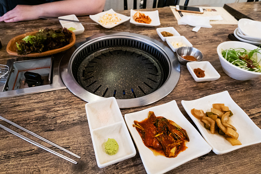 Korean cuisine - empty dripping pan and various served side dishes in korean BBQ restaurant in Seoul city