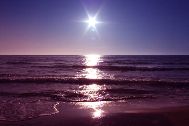 le soleil se couche sur la mer au coucher du soleil, à l'horizon, il ressemble à une fausse étoile. la mer est calme devant une plage de sable fin à versilia, toscane, italie - water wave sea tranquil scene photos et images de collection