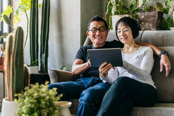 istock Chinese couple on sofa with tablet smiling and enjoying the internet 1188040479