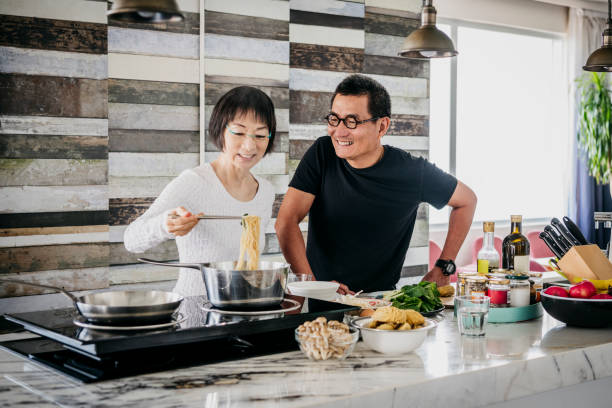istock Cheerful Chinese couple making noodles in kitchen 1188040480