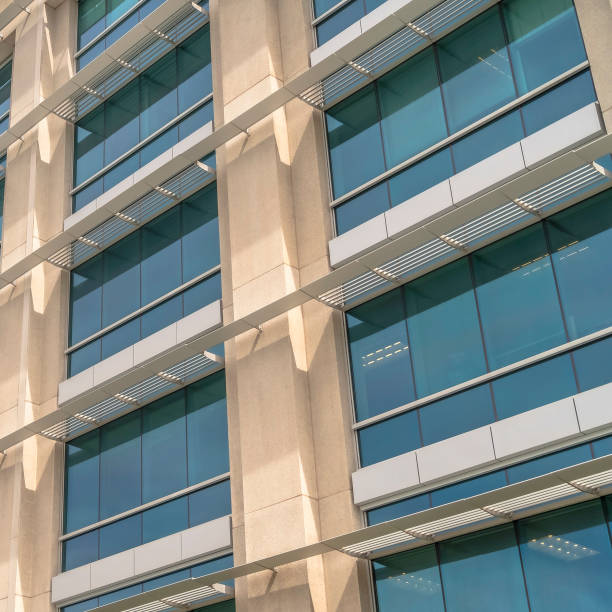 istock Square Modern building facade close up with glass windows and sunlit concrete wall 1188043509