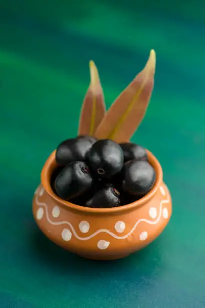 Jambolan plum or jambul or Jamun fruit, Java plum (Syzygium cumini) on textured background.