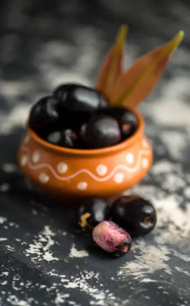 Jambolan plum or jambul or Jamun fruit, Java plum (Syzygium cumini) with leaf on stone textured background.