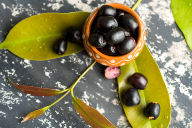 istock Jambolan plum or jambul or Jamun fruit, Java plum (Syzygium cumini) with leaf on stone textured background. 1188044852