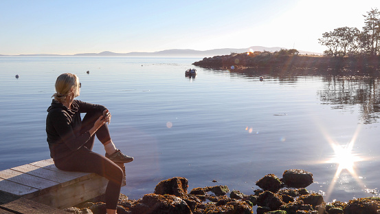 She looks off to distant scene with cell phone in hand