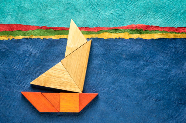 abstract picture of a sailing boat built from seven tangram wooden pieces over a landscape created with handmade textured bark paper, travel and vacation concept, copyright by the photographer