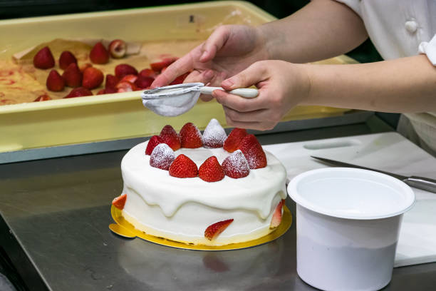 istock Female pastry chef hands, decorating a strawberries cake with powdered sugar 1188055692