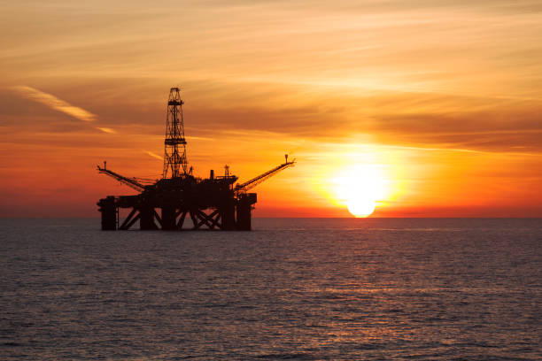 Silhouette of offshore oil rig at sunset stock photo