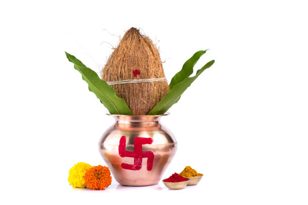 Copper Kalash with coconut, mango leaf, Haldi, kumkum and sweets with marigold flower decoration on a white background. Essential in Hindu puja. stock photo