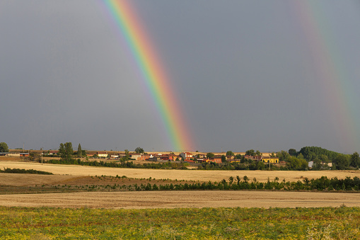 Double Rainbow in summer landscape with village and trees