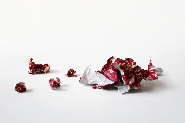 A perspective shot of crumpled balled pieces of red Christmas or Holiday wrap, laid out on a flat surface.  A perfect template to Photoshop clearcut items onto for a festive layout.