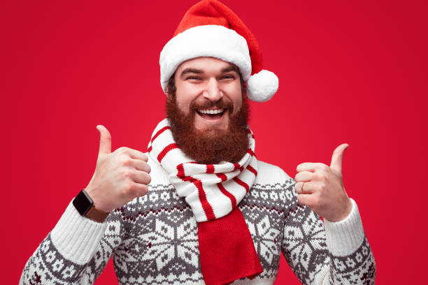 istock Cheerful guy in Christmas hat gesturing thumb ups 1188089324