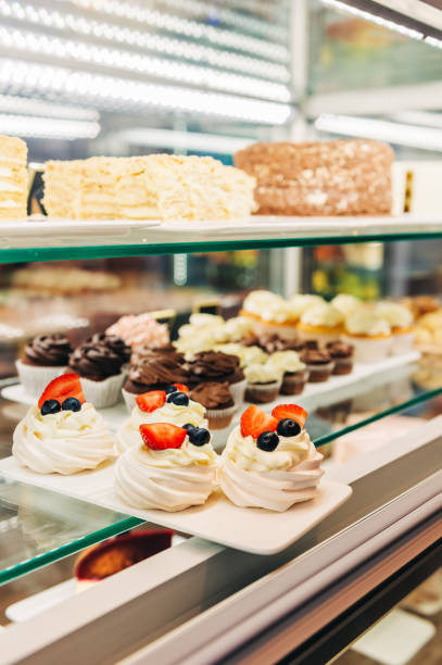 istock Shop window with chocolate cupcakes and meringue dessert at bakery store 1188093312