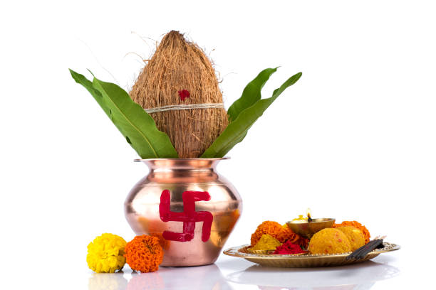 istock Copper Kalash with coconut and mango leaf and pooja thali with diya, kumkum and sweets with floral decoration on a white background. Essential in hindu puja. 1188099853