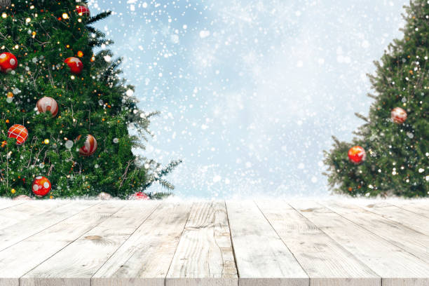 istock Top of empty wood table with beautiful Christmas tree and snowfall  backdrop 1188105180