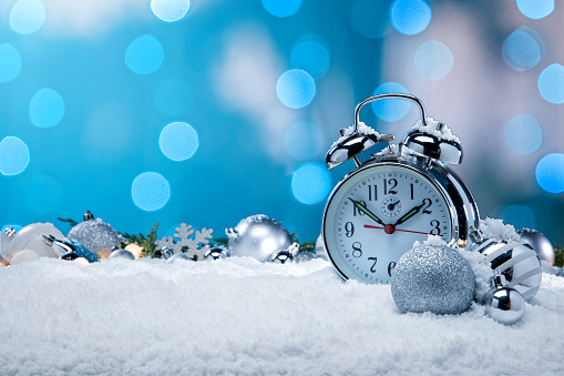 This is a photo of an Alarm Clock and Christmas Ornaments in the bed sitting in a snow background.