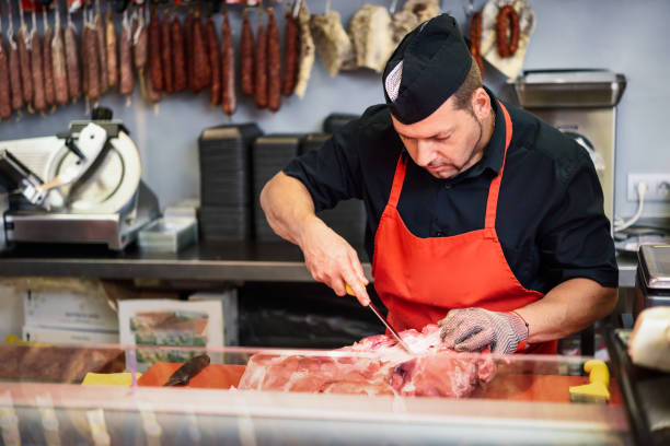 Butcher boning fresh ham in a modern butcher shop stock photo