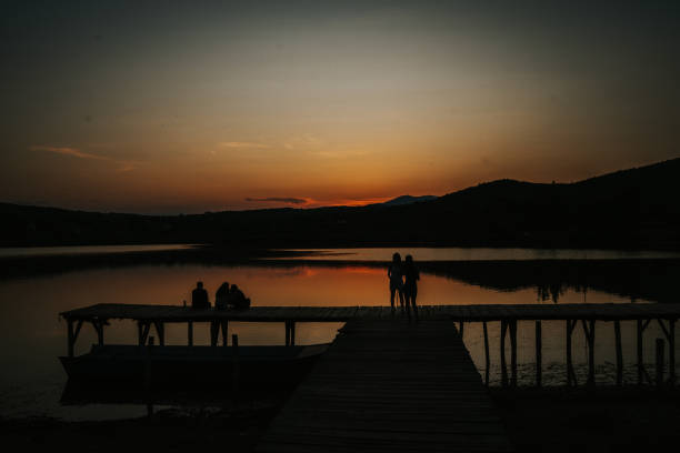 Friends enjoying sunset on lake pier