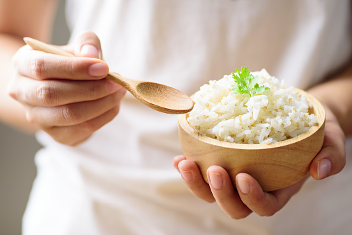 Hand holding spoon for eating cooked rice with quinoa seed in a bowl, healthy food
