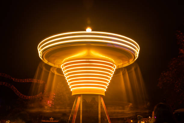 um carrossel colorido borrado no movimento no parque de diversões, iluminação da noite. longa exposição. - ferris wheel wheel blurred motion amusement park - fotografias e filmes do acervo