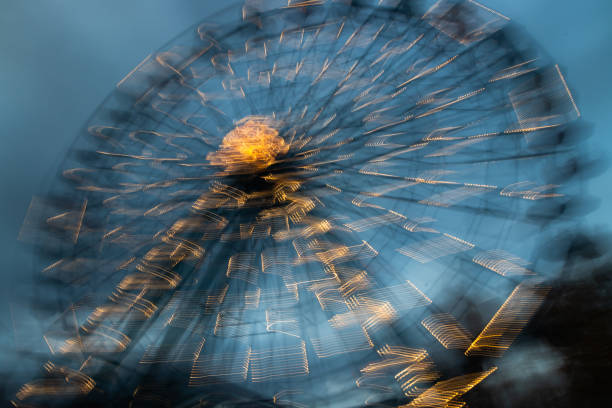 ruota panoramica sfocata in movimento al parco divertimenti, illuminazione notturna. lunga esposizione. - ferris wheel wheel blurred motion amusement park foto e immagini stock
