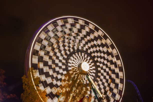 ruota panoramica in movimento al parco divertimenti, illuminazione notturna. lunga esposizione. - ferris wheel wheel blurred motion amusement park foto e immagini stock