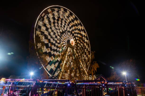 ruota panoramica in movimento al parco divertimenti, illuminazione notturna. lunga esposizione. - ferris wheel wheel blurred motion amusement park foto e immagini stock