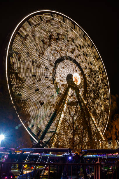 ruota panoramica in movimento al parco divertimenti, illuminazione notturna. lunga esposizione. - ferris wheel wheel blurred motion amusement park foto e immagini stock